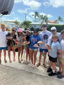 Group of young anglers displaying their catch on a fishing dock in Little Torch Key FL