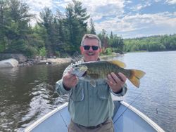 A fisherman holding a large smallmouth bass in Ontario, Canada