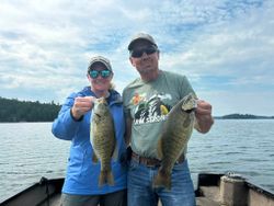 Two anglers displaying caught smallmouth bass on fishing boat at Nestor Falls ON
