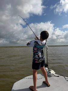 Angler fishing from boat with bent rod indicating fish hooked in Matagorda TX waters