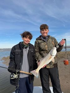 Two young anglers display a caught redfish on the shore in Matagorda TX