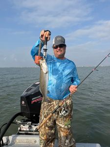 Angler holds freshly caught speckled trout on fishing boat in Matagorda TX waters