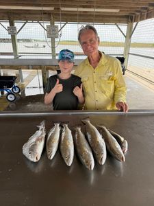 Successful fishing trip in Matagorda TX showing caught speckled trout and redfish laid out on cleaning station