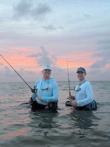 Two anglers wade fishing in coastal waters near Matagorda TX at sunset with fishing rods