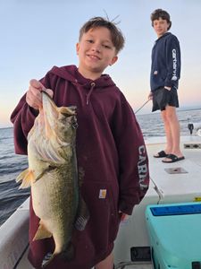 Proud young angler with a chunky largemouth bass on a family fishing trip
