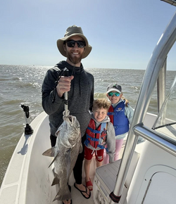 A fisherman holds up a large black drum fish caught in Galveston