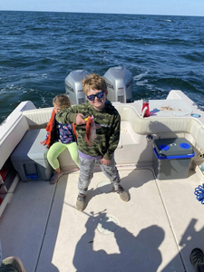 Two people fishing on Dauphin Island with a 14-inch fish