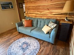 Cozy cabin interior with blue sofa and wood paneling in Hale MI fishing lodge