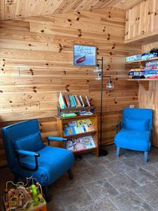 Cozy wooden reading corner with blue chairs and book display at fishing lodge in Hale MI