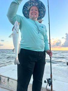 Angler holding caught fish on fishing boat in Matagorda TX waters at sunset