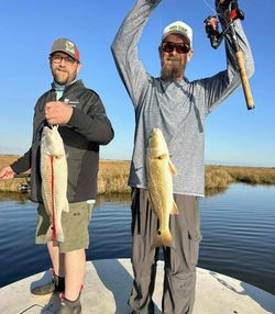 Two anglers displaying caught redfish on boat in Matagorda TX waters