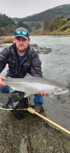 Rainbow trout caught fishing in Myrtle Creek OR with fishing rod visible by river