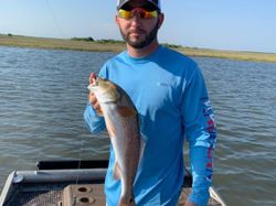 A lone fisherman reeling in a 15-inch catch in TX
