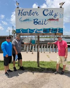 Fishing guides standing beside Harbor City Bait shop sign in Rockport TX