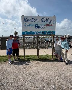Harbor City Bait shop sign with fishing charter boats docked in background at Rockport TX marina