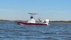 Red and white fishing boat on water in Corpus Christi TX with outriggers and fishing equipment