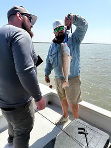 Two anglers holding a small 19-inch fish in TX