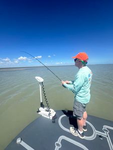 Angler fishing from boat deck with bent rod indicating fish on line in Rockport TX waters