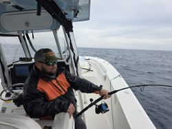 Fishing from boat deck in Hampton VA waters with fishing rod extended over ocean
