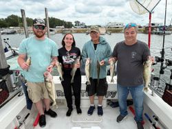 Four anglers displaying fresh caught walleye on fishing charter boat in Oregon OH marina