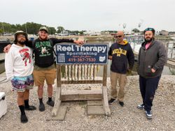 Fishing group displaying walleye catch at Oregon OH marina with Reel Therapy Sportfishing sign