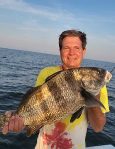 A fisherman holds a large black drum fish caught in Oxford