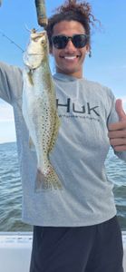A person fishing in FL, catching a spotted weakfish.