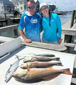 Successful fishing trip in Morehead City NC showing redfish and Spanish mackerel catch on cleaning table at marina dock