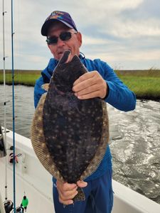 Angler holding summer flounder caught in Manns Harbor