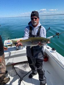 Photograph of a fisherman holding a large rainbow trout in Buffalo