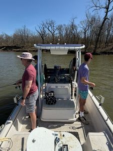 Fishing boat on calm water near wooded shoreline in Mannford OK with center console and T-top