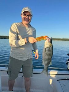 Angler holding freshly caught striped bass on boat in Mannford OK
