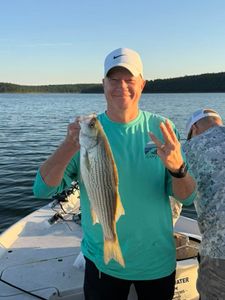 Angler holding striped bass catch on fishing boat in Mannford OK