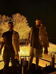 Two anglers display their Common Carp catch during nighttime fishing in Orange TX
