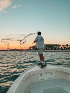 Cast net being thrown from boat bow in Florida waters at sunset