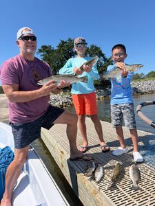Successful fishing trip in Gulf Shores AL with speckled trout and redfish catch displayed on dock