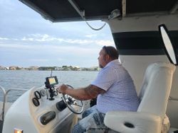 Boat captain at helm with navigation equipment on water near Fort Walton Beach FL coastline