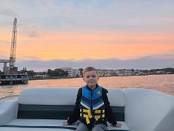 Tour boat on calm water during sunset in Fort Walton Beach FL with waterfront buildings and pier in background