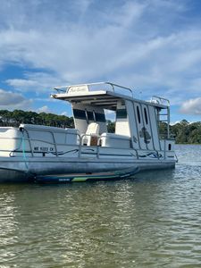 White pontoon boat with upper deck and canopy anchored in calm waters near Fort Walton Beach FL for tours