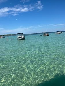 Crystal clear turquoise waters with pontoon boats anchored in Fort Walton Beach FL shallow bay area