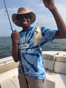 An angler posing with a 7-inch Atlantic Croaker fish caught in GA