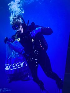 Scuba diver underwater in Florida City FL collecting debris in mesh bag during ocean cleanup dive