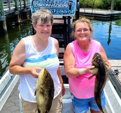 Two anglers displaying freshly caught bass on fishing boat dock in Hudson FL