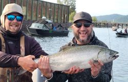Two anglers holding a large Coho salmon catch in Portland OR