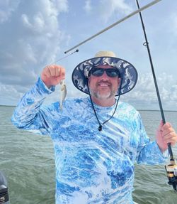 Angler holding small fish catch with fishing rod on boat in Apalachicola FL waters
