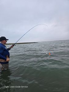 Angler wade fishing in shallow water at Point Comfort TX with bent fishing rod