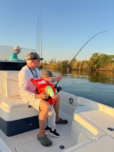 Fishing scene on boat with bent rod indicating fish on line in Port Arthur TX waters
