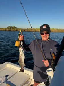 Angler holding freshly caught speckled trout on fishing boat in Port Arthur TX waters