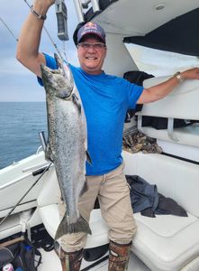 A fisherman holding a large chinook salmon caught while fishing in ON
