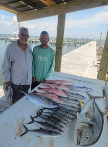 Two anglers holding three blue runner and spanish mackerel fish in Gulf Shores